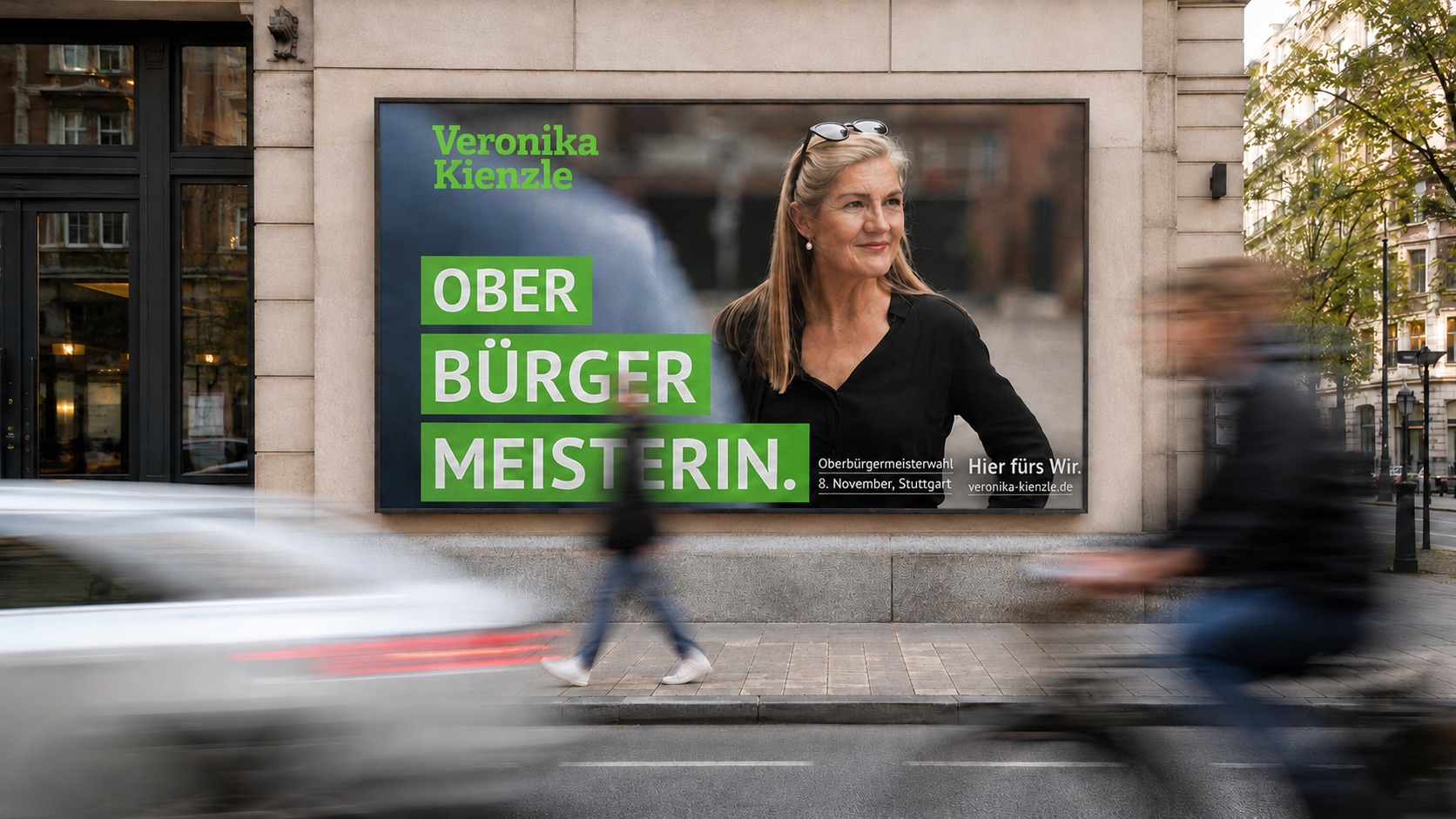 Wahlkampfplakat von Veronika Kienzle an einer Hauswand: „OBERBÜRGERMEISTERIN.“ neben einem Portraitfoto, davor eine belebte Straße